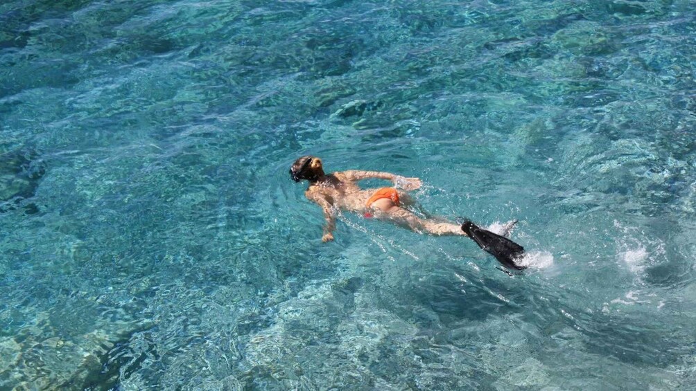 A person swimming in clear blue water. 4