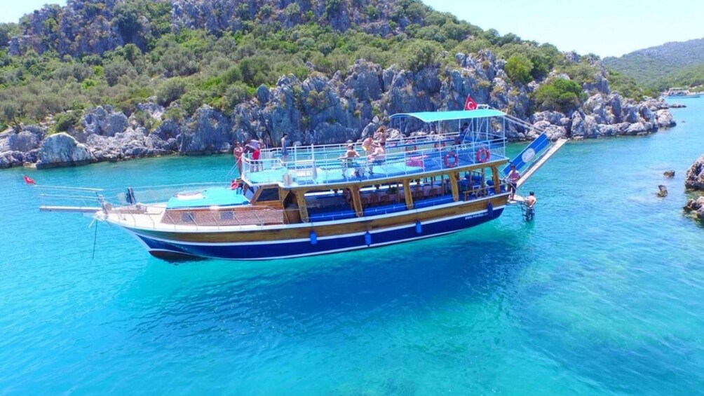 A boat with passengers, surrounded by clear turquoise water and rocky terrain. 2