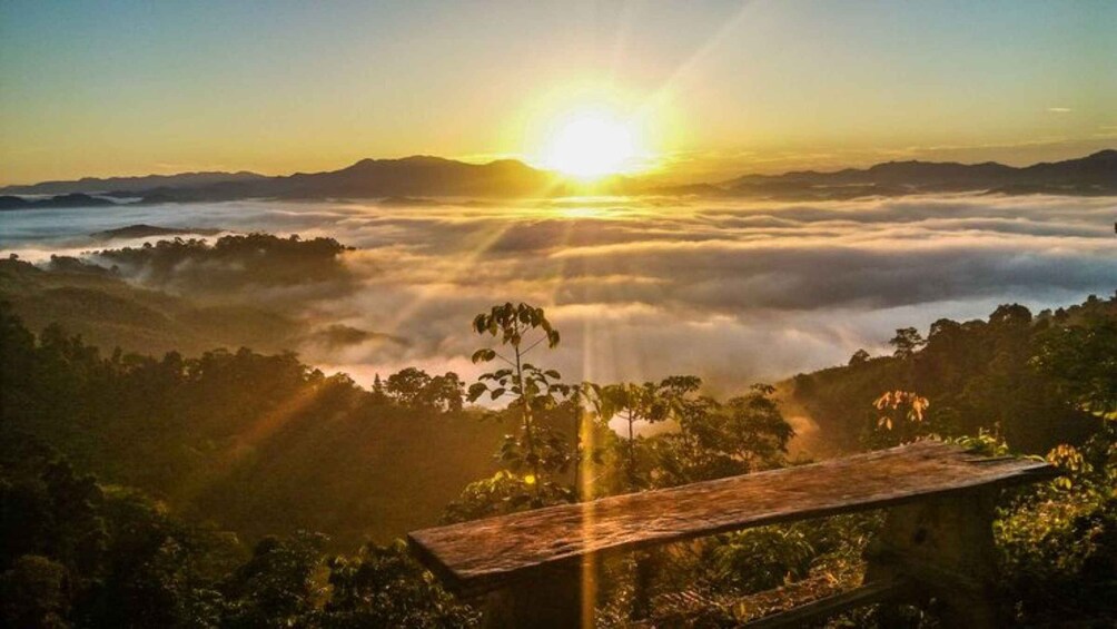 A sunrise over a mountainous landscape with a wooden bench in the foreground. 1