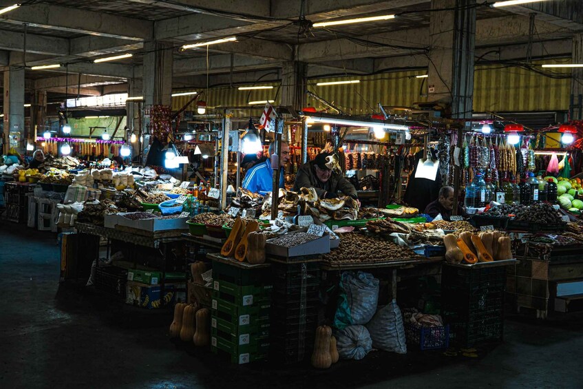 An indoor market with various stalls selling fruits, vegetables, and other goods. 4