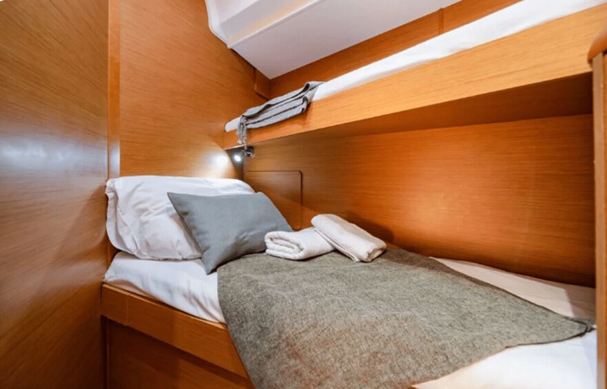 A compact cabin with a bunk bed, a small table with a towel, and a headboard. 5