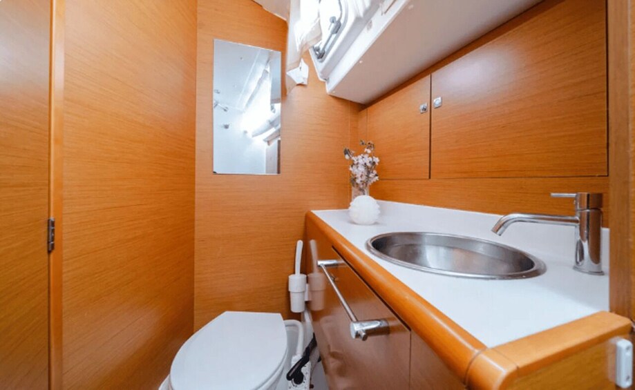 A compact bathroom with a white toilet, a sink, and a mirror. 1