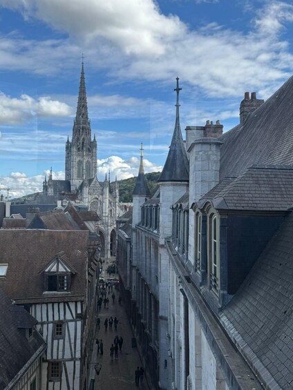 A cathedral with a tall spire, a narrow street lined with buildings, and a clear blue sky. 3