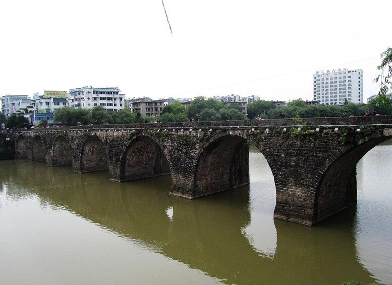 A stone bridge over a river with buildings in the background. 2