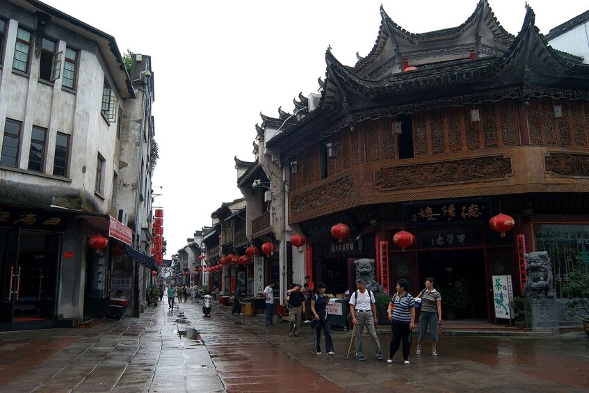 A wet street in a traditional Chinese town with ornate buildings and red lanterns. 3
