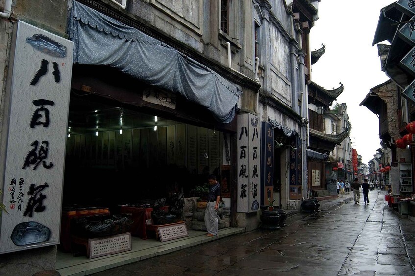 A traditional street with shops, a wet pavement, and traditional architecture. 4