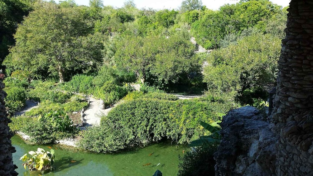 A lush green landscape with a water body and stone structures. 3