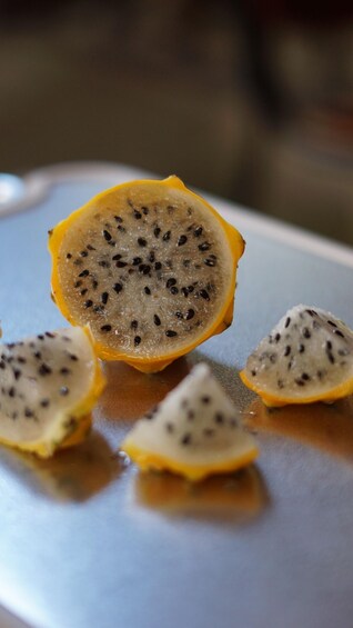 A sliced dragon fruit with black seeds on a white plate. 2