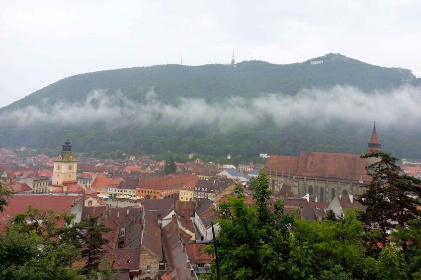 A town with red-roofed buildings, a prominent church, and a hill with a tower in the background. 5