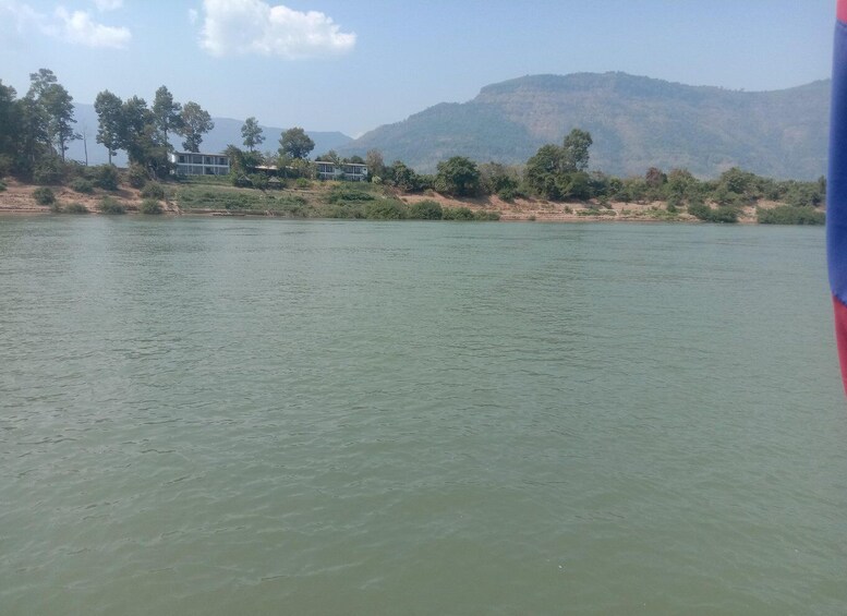 A calm river with a distant view of a hill and a building. 2