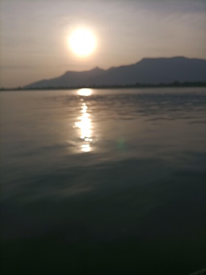 A body of water reflecting the sun with mountains in the background. 3