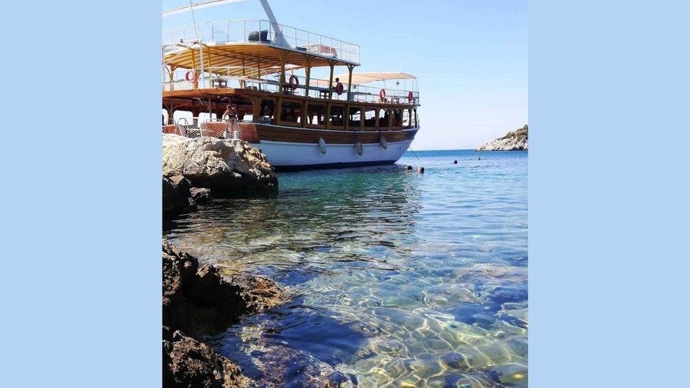 A boat docked at a rocky shore with clear water. 3