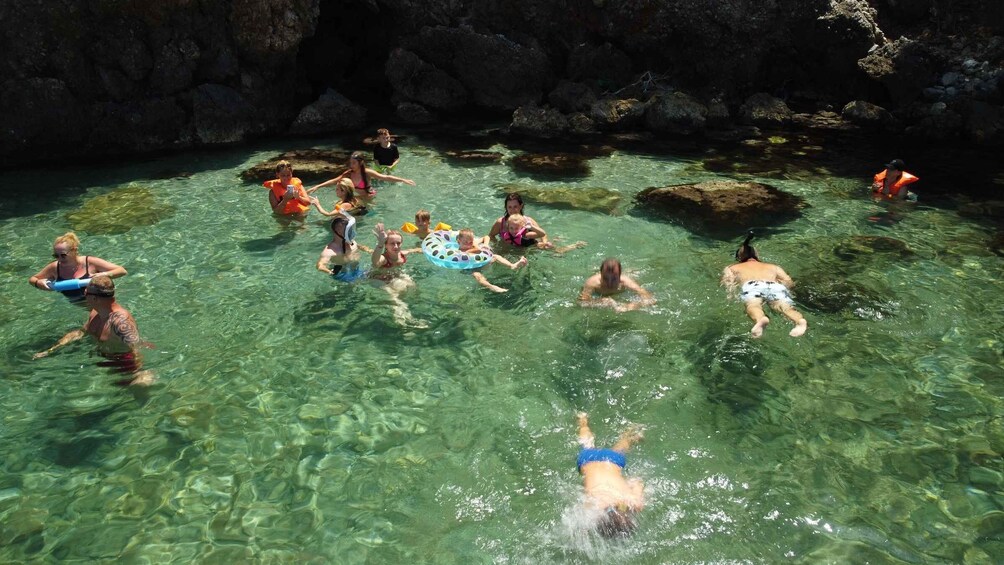 People swimming in a clear, rocky pool surrounded by cliffs. 2