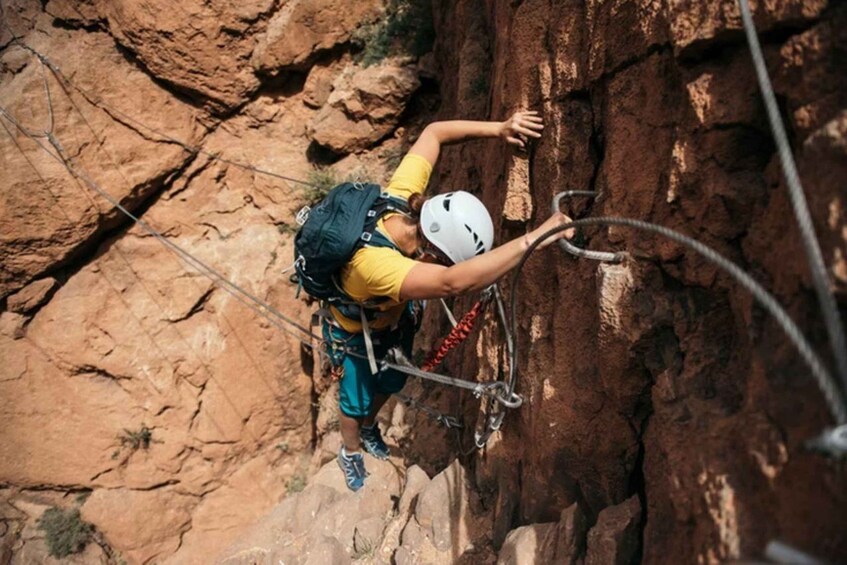 A person climbing a rocky cliff with a helmet and harness. 1