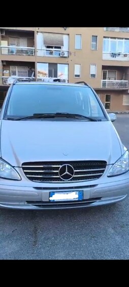 A silver Mercedes-Benz parked in front of a residential building with balconies. 5