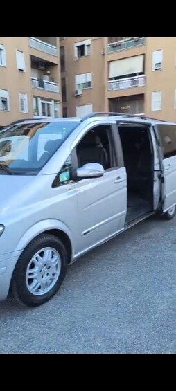 A silver van parked on a street with a building in the background. 3