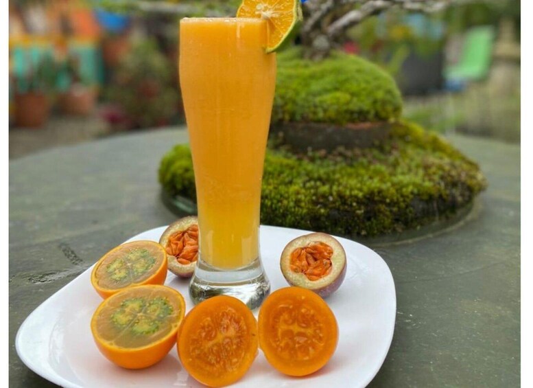 A tall glass of orange juice with a slice of orange on the rim, surrounded by halved passion fruits on a white plate. 2