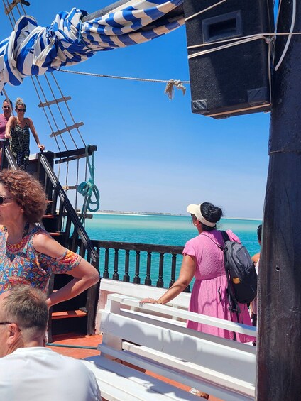 A group of people on a ship deck overlooking turquoise waters. 5
