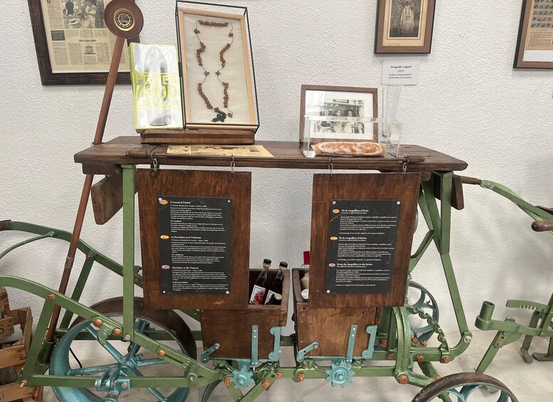 A vintage cart with two informational signs, a framed picture, and a bottle. 3