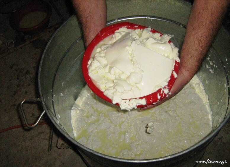 A person mixing a creamy substance in a large metal bowl. 2