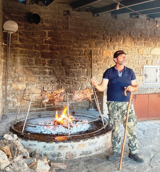 A man grilling meat on a traditional outdoor grill with a fire burning underneath. 3