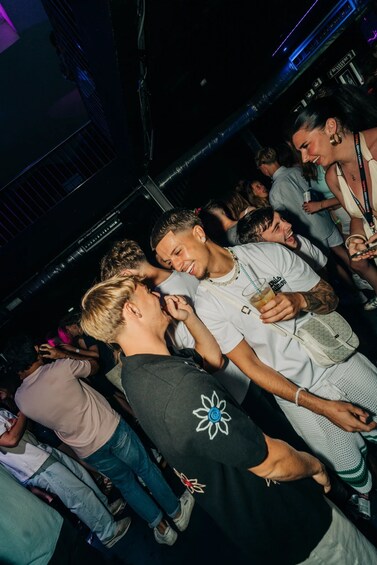 A crowded indoor social scene with people standing and conversing. 3