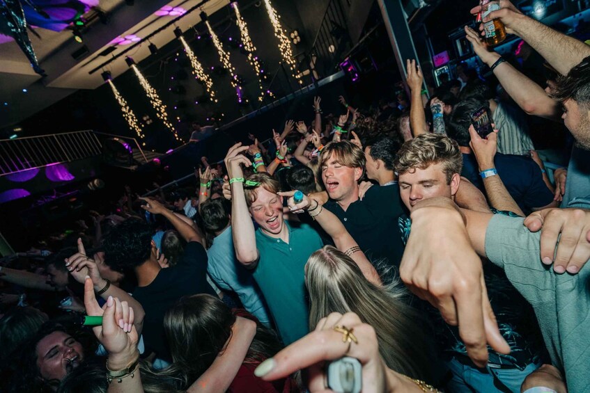 A crowded indoor event with people holding drinks and engaging in social activities. 1