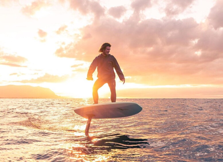 A person surfing on a wave at sunset. 1