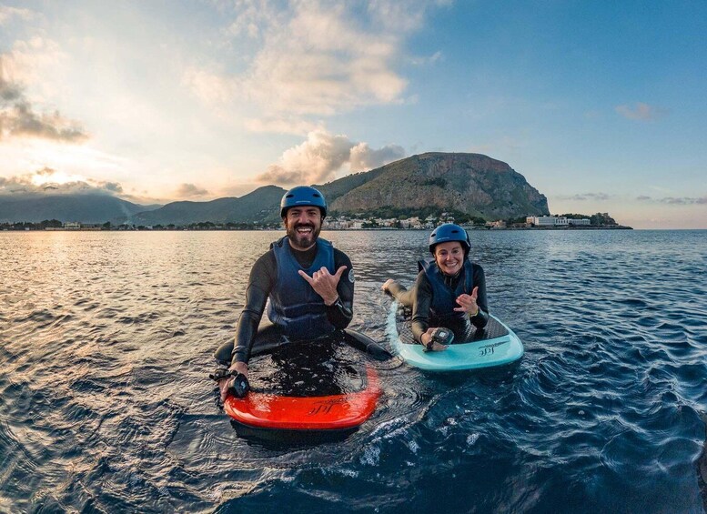 Two people on a water sport, a body of water, and a distant mountain. 3
