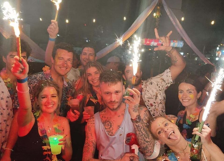 A group of people at a party with sparklers and drinks. 2
