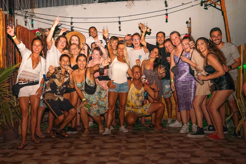 A group of people posing for a photo in an outdoor setting with a tiled floor and a wooden fence in the background. 1