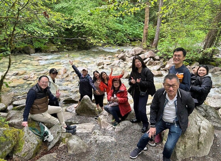 A group of people posing by a rocky stream in a forested area. 1