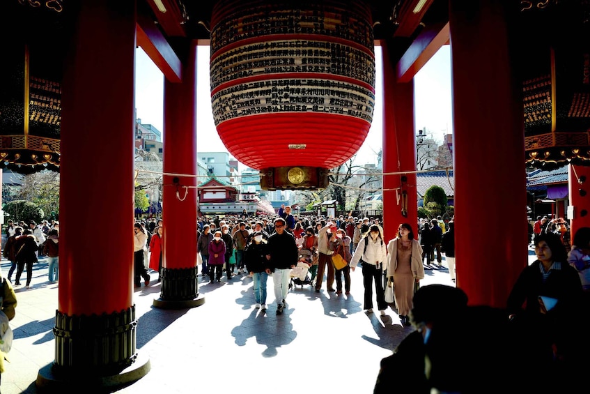 A crowded plaza with red pillars and a large red lantern. 2