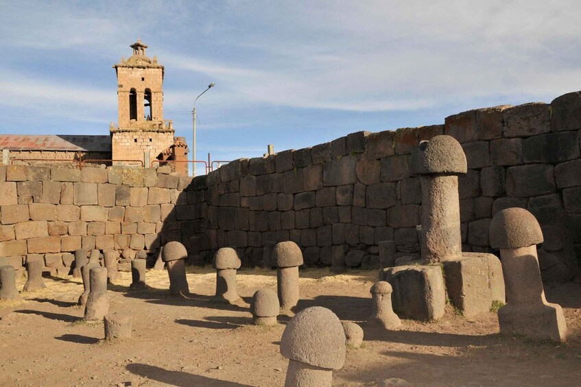 A historical stone wall with a watchtower and spherical stone bollards. 1