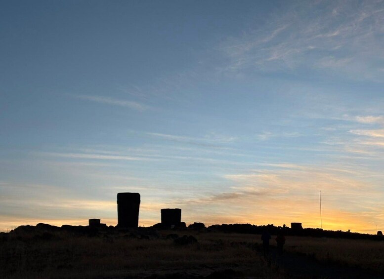 A sunset over a field with two large stone structures. 4