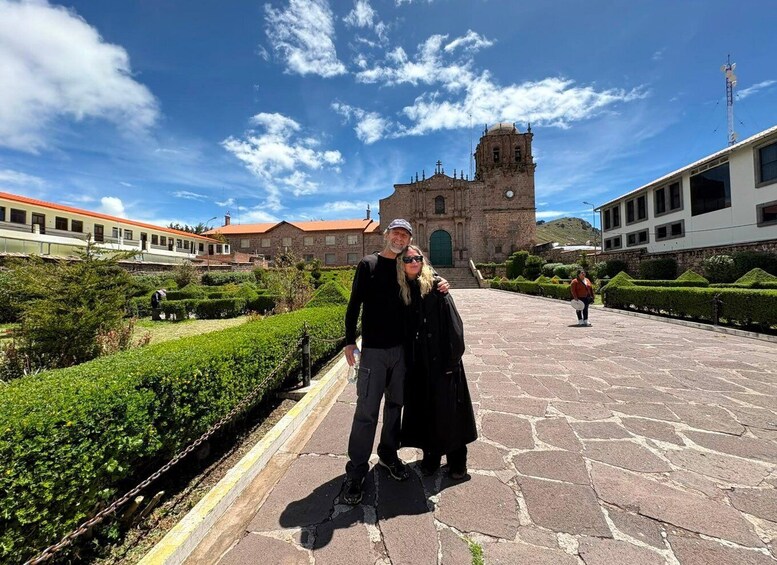A historic church with a bell tower, a paved courtyard, and neatly trimmed hedges. 5