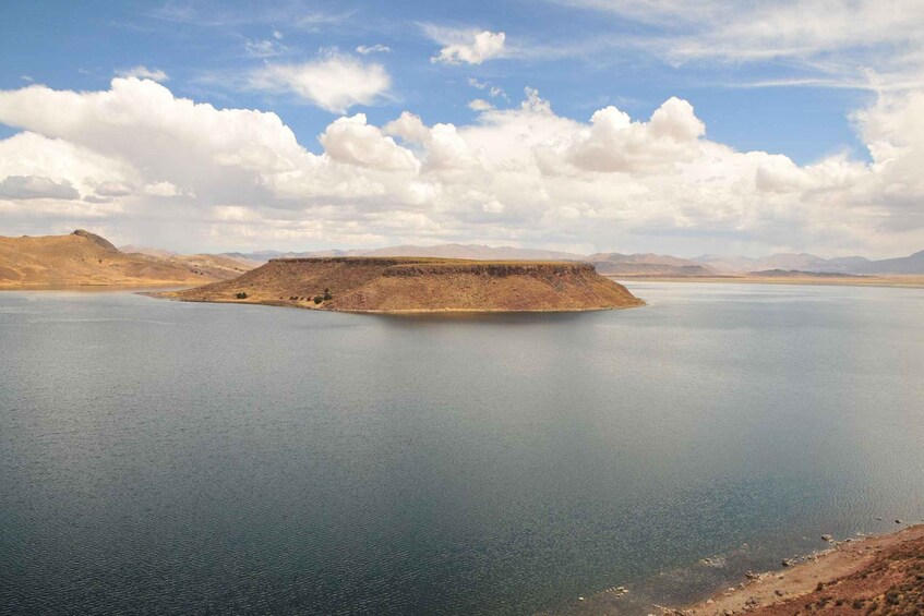 A large body of water with a flat island in the center surrounded by hills. 3