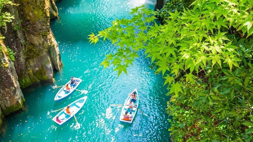 Three canoes on a turquoise river surrounded by greenery and rocky cliffs. 1