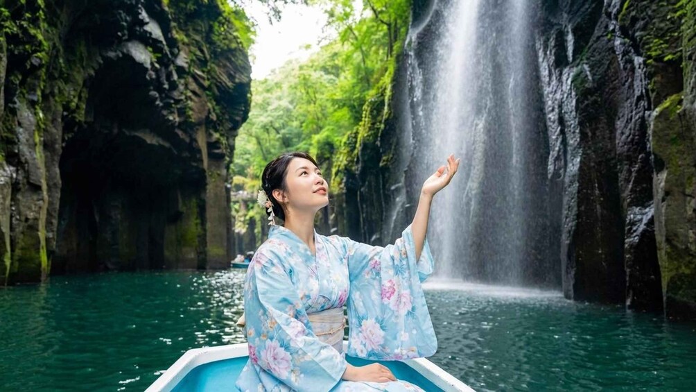 A person in a boat wearing a floral kimono, with a waterfall in the background. 5