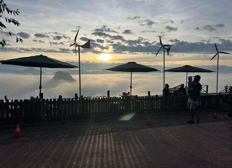 A sunset view with wind turbines and umbrellas on a wooden deck. 2