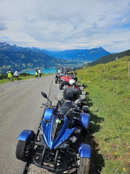 A row of blue motorcycles parked on a road with a mountainous landscape in the background. 3