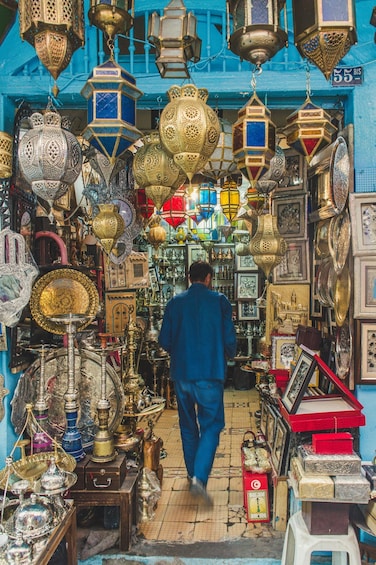 A man walking through a shop filled with ornate lanterns and decorative items. 3