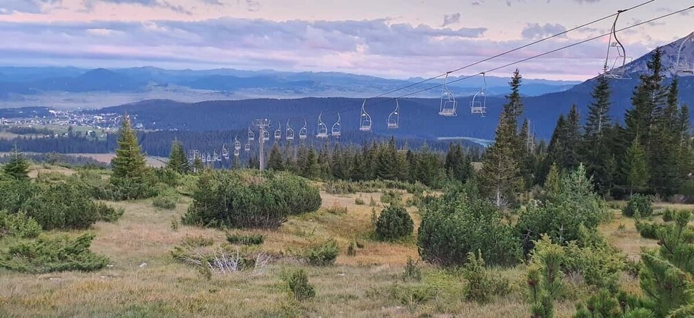A mountain landscape with ski lifts, trees, and a distant town. 2