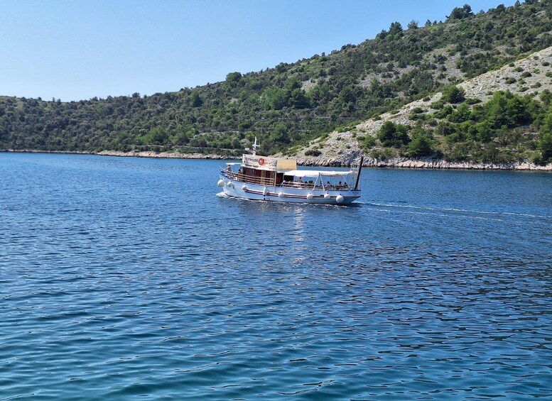 A boat named 'PAX' on a calm body of water with a hilly, forested shoreline in the background. 5