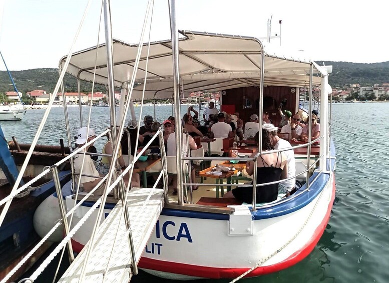 A boat with people dining, anchored near a marina with buildings in the background. 4