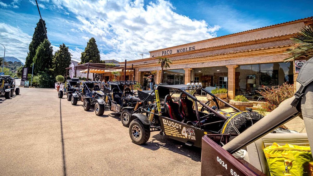 A line of off-road vehicles parked in front of a building with 'PACO MOBLES' signage. 4