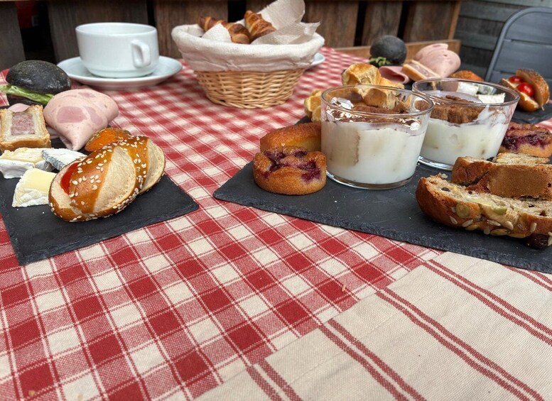 A picnic setup with various breads, cheese, and a glass of milk on a checkered tablecloth. 2