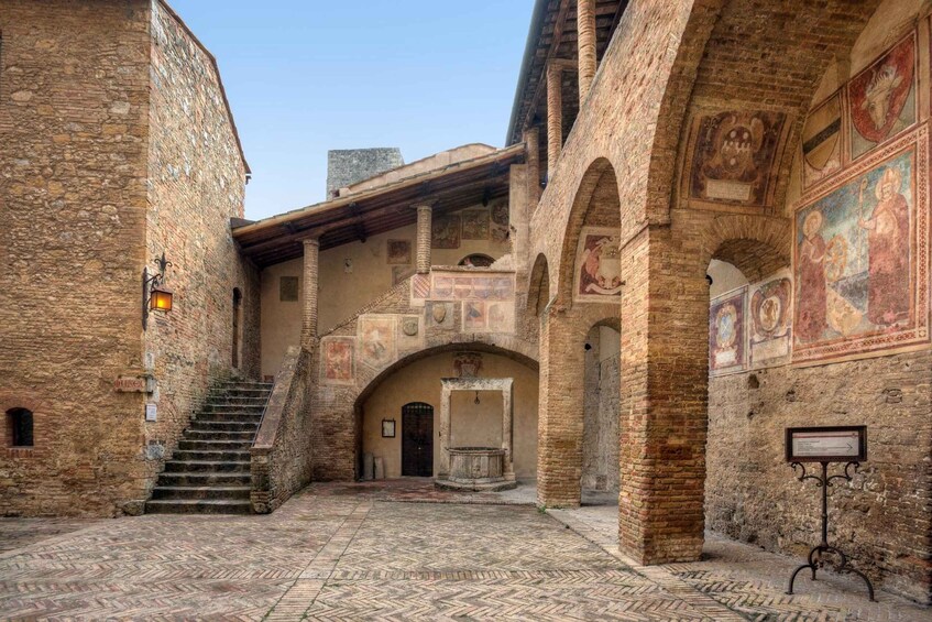 An ancient stone building with a tiled courtyard, arched doorways, and frescoes. 2