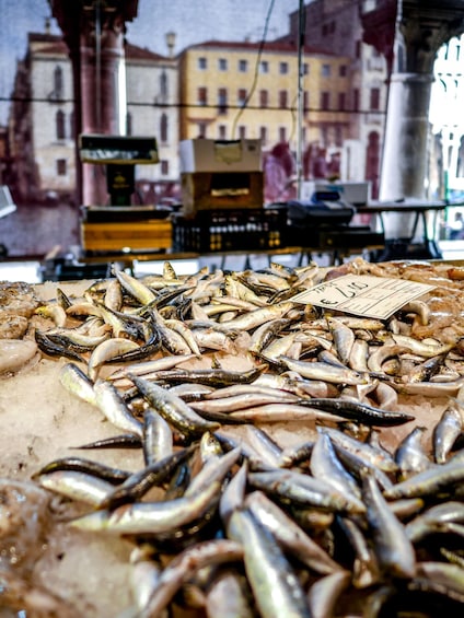 A variety of fish on ice in a market setting with buildings in the background. 1