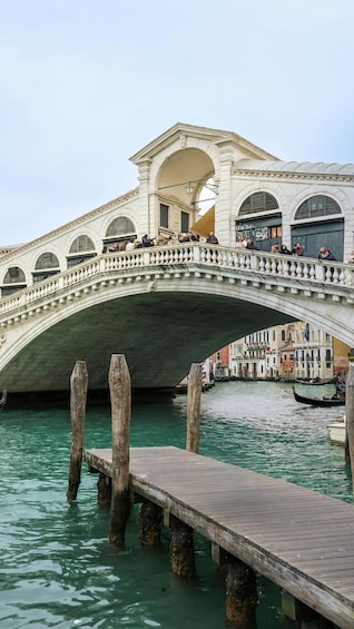 A stone bridge with balustrades, wooden posts, and a wooden walkway over water. 3
